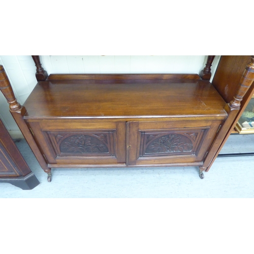 104 - A late Victorian mahogany carved buffet with two inline drawers, over an open shelf and two door cup... 