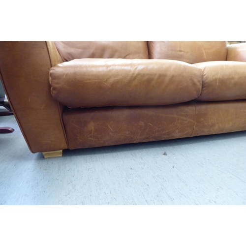 137 - A modern two person settee upholstered in stitched brown hide with a straight back and level arms&nb... 