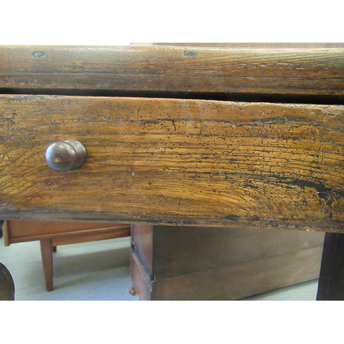 152 - An early 18thC rustically constructed elm and oak two drawer dresser, raised on carved and pierced p... 