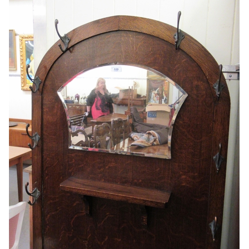 189 - A 1930s oak hallstand with an arched panelled back, a mirror, eight hooks and a hinged seat, flanked... 