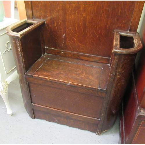 189 - A 1930s oak hallstand with an arched panelled back, a mirror, eight hooks and a hinged seat, flanked... 