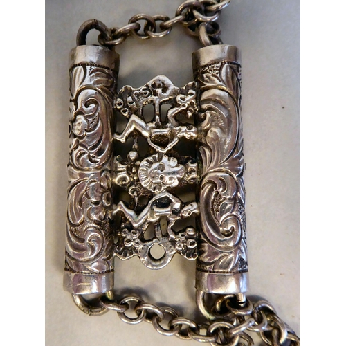 23 - White coloured metal items: to include an ornately cast tablet and chain link belt