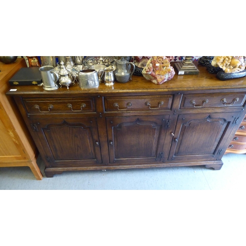 234 - A modern Old English style oak dresser, comprising three frieze drawers, over three inline fielded p... 