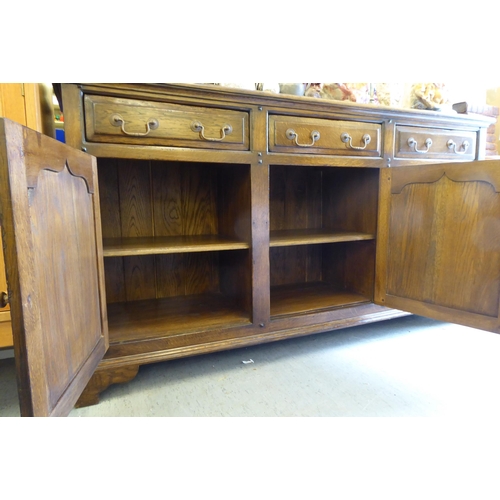 234 - A modern Old English style oak dresser, comprising three frieze drawers, over three inline fielded p... 