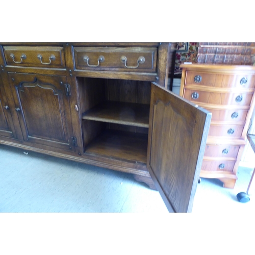 234 - A modern Old English style oak dresser, comprising three frieze drawers, over three inline fielded p... 