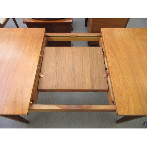 260 - A 1970s teak dining table with an integral additional leaf, raised on tapered legs  29