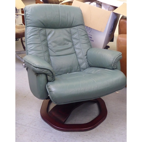 276 - A modern cushioned pale green soft hide upholstered, adjustable lounge chair with enclosed arms, rot... 