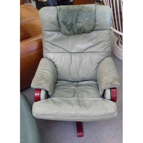 277 - A modern cushioned pale green soft hide upholstered, adjustable lounge chair with enclosed arms, rot... 