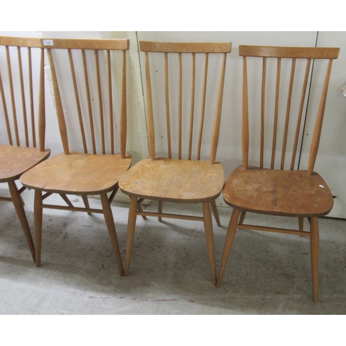 280 - A set of seven Ercol beech and elm framed spindle back dining chairs, the solid seats raised on turn... 