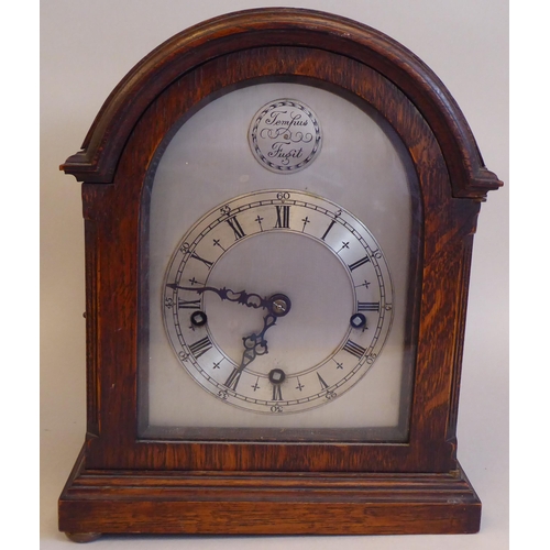 61 - An early 20thC round arch, oak cased bracket clock; the gong strike movement faced by a silvered and... 