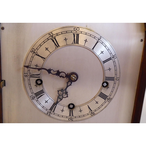 61 - An early 20thC round arch, oak cased bracket clock; the gong strike movement faced by a silvered and... 