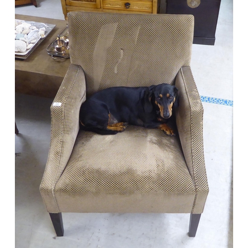 83 - A modern patterned fabric covered enclosed armchair, raised on square, tapered legs