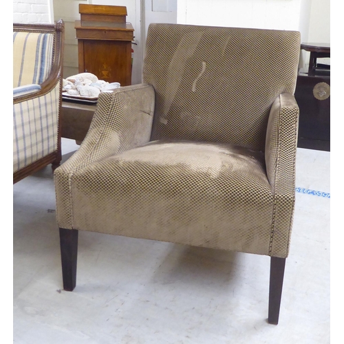 83 - A modern patterned fabric covered enclosed armchair, raised on square, tapered legs