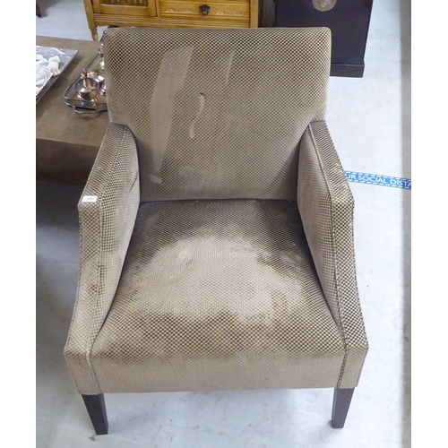 83 - A modern patterned fabric covered enclosed armchair, raised on square, tapered legs