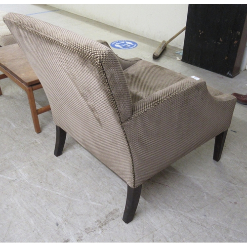 83 - A modern patterned fabric covered enclosed armchair, raised on square, tapered legs