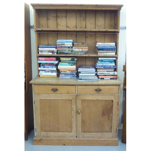 97 - An early 20thC pine dresser with a three tier plate rack, over two drawers and two panelled doors, o... 