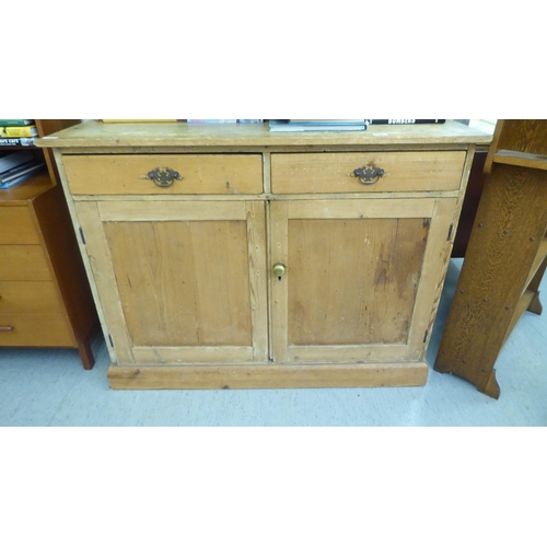 97 - An early 20thC pine dresser with a three tier plate rack, over two drawers and two panelled doors, o... 