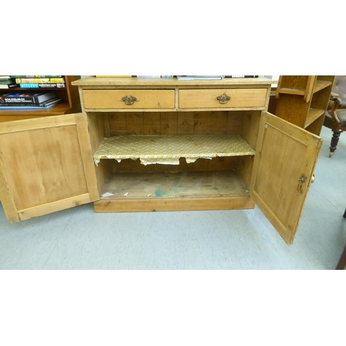 97 - An early 20thC pine dresser with a three tier plate rack, over two drawers and two panelled doors, o... 