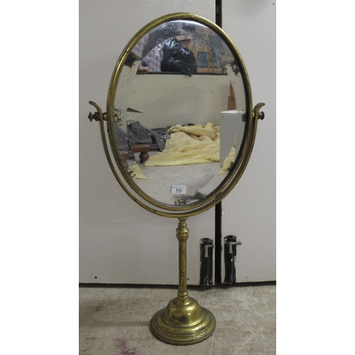 194 - An early 20thC brass framed dressing room toilet mirror, the bevelled plate pivoting/rotating on a t... 