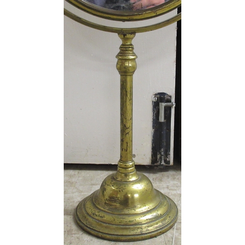 194 - An early 20thC brass framed dressing room toilet mirror, the bevelled plate pivoting/rotating on a t... 