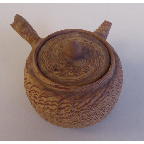 199 - An antique Japanese agate ware Saki pot of bulbous form with a short spout, side handle and cover