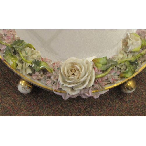 222 - A late 19thC (probably German) oval dressing table mirror, the bevelled plate set in a floral encrus... 