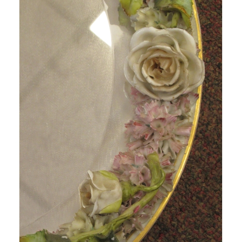 222 - A late 19thC (probably German) oval dressing table mirror, the bevelled plate set in a floral encrus... 