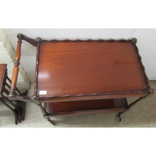 349 - A Victorian style mahogany two tier serving trolley, the uppermost with a wavy edged gallery, on sle... 