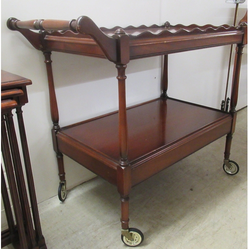 349 - A Victorian style mahogany two tier serving trolley, the uppermost with a wavy edged gallery, on sle... 