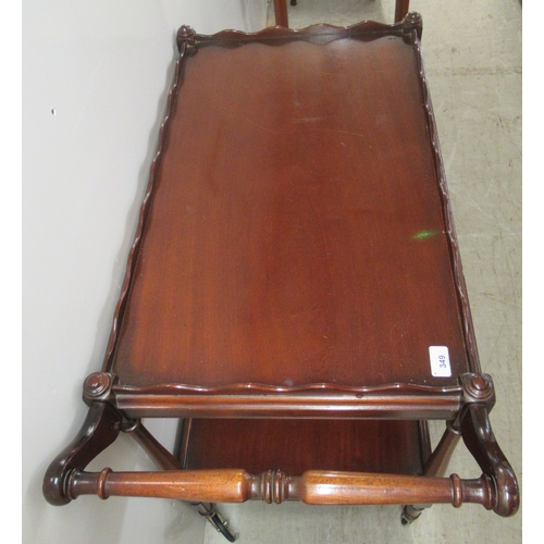 349 - A Victorian style mahogany two tier serving trolley, the uppermost with a wavy edged gallery, on sle... 