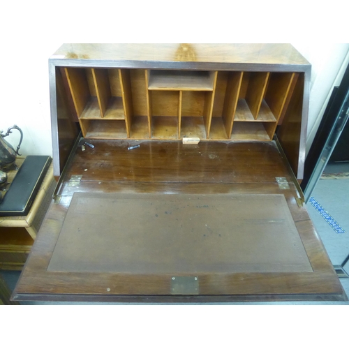 82 - A 1930s walnut finished clerks bureau. the fall flap enclosing a part fitted interior, raised on sle... 