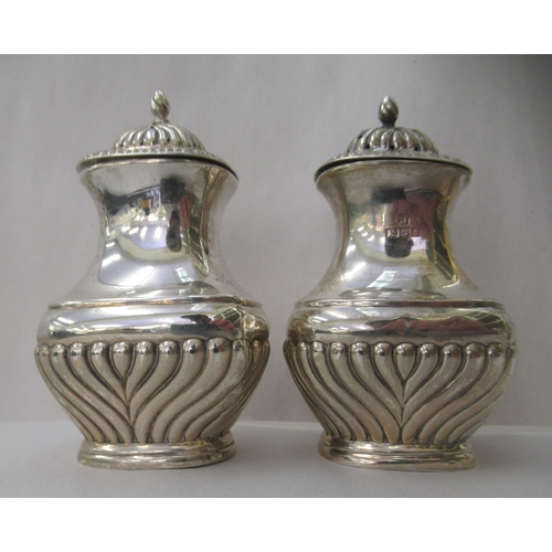 57 - A three piece silver condiments set of oval demi-reeded form  comprising two pepper pots; and a... 