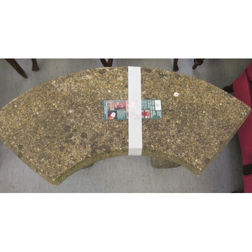 20 - A composition stone garden seat, the curved top upon two squirrel pedestals  17