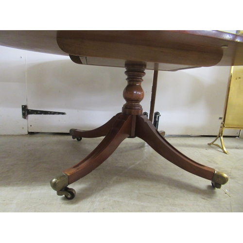 138 - A reproduction mahogany finished oval coffee table, raised on splayed legs with brass capped casters... 