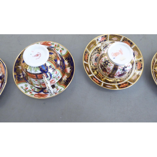 168 - Five Royal Crown Derby china cups and saucers, decorated in the Imari palette with gilding