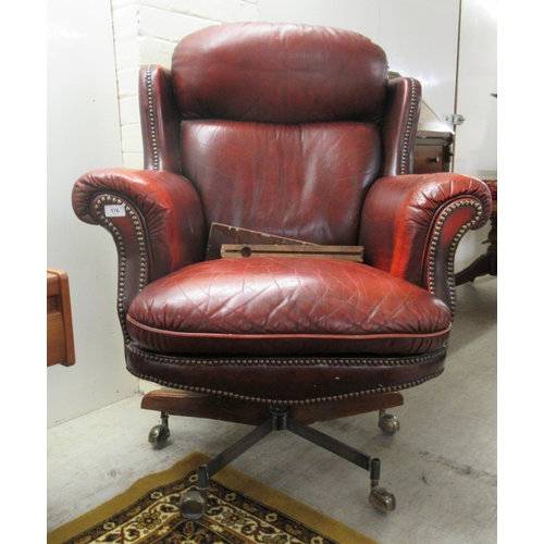 176 - A 20thC desk chair, stud upholstered in ox blood coloured hide, on a swivel base, splayed legs and c... 