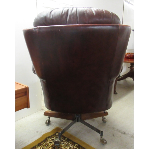 176 - A 20thC desk chair, stud upholstered in ox blood coloured hide, on a swivel base, splayed legs and c... 