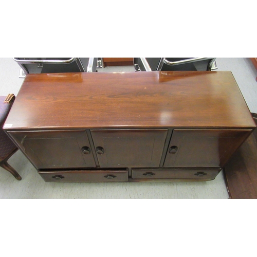 219 - An Ercol dark stained elm sideboard with three doors, over two inline drawers, on a plinth and caste... 