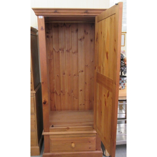 298 - A modern pine hallrobe with a panelled door, over a base drawer, on a plinth  70