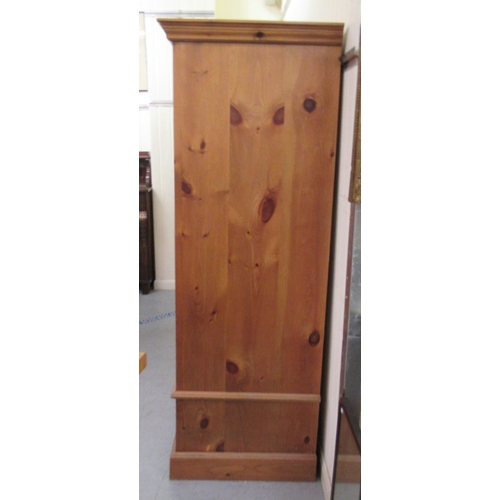 298 - A modern pine hallrobe with a panelled door, over a base drawer, on a plinth  70