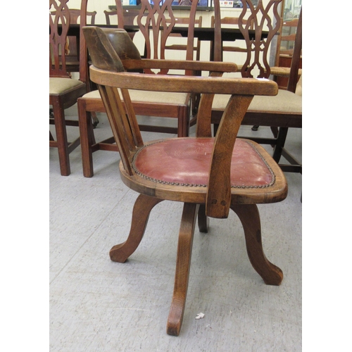 299 - An early 20thC stained beech framed, open arm desk chair, the stud upholstered hide seat raised on a... 