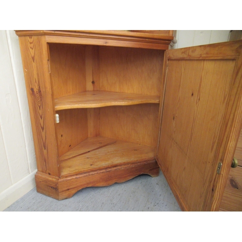 302 - A modern pine two part corner cabinet, the superstructure with two open shelves, over a panelled doo... 