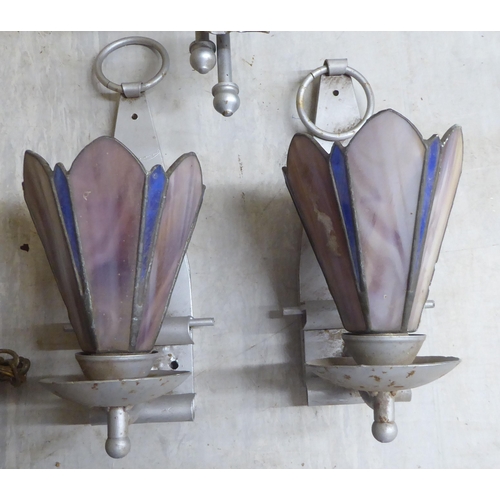 62 - Early 20thC lighting, in stylised silvered fittings: to include two pairs of wall lamps with coloure... 