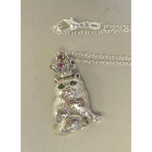 15 - A silver coloured metal novelty pendant, a seated cat with ruby eyes, wearing a crown, on a fine nec... 