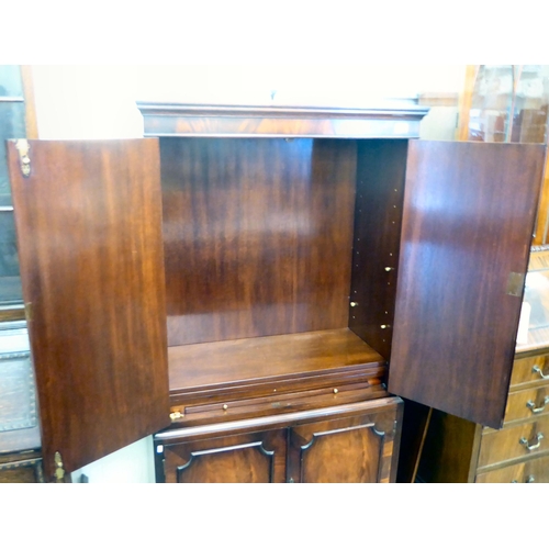 100 - A modern flame mahogany finished cabinet, the upper section with a pair of panelled doors and an int... 