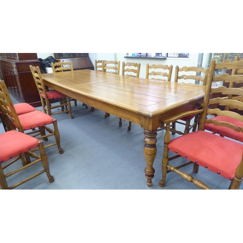 25 - An 'aged' antique style honey coloured hardwood dining table, the dowelled plank panelled top over t... 