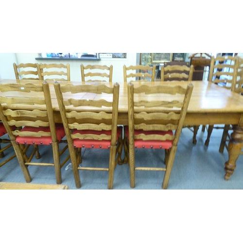 25 - An 'aged' antique style honey coloured hardwood dining table, the dowelled plank panelled top over t... 