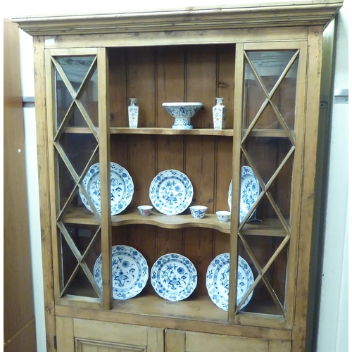 30 - A 19thC and later waxed pine display cabinet, the partially enclosed upper part with open shelves an... 