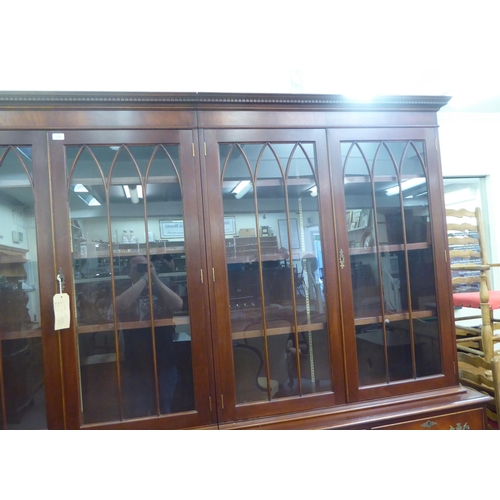 57 - A 20thC reproduction of a Georgian mahogany library bookcase, the upper section with three pairs of ... 