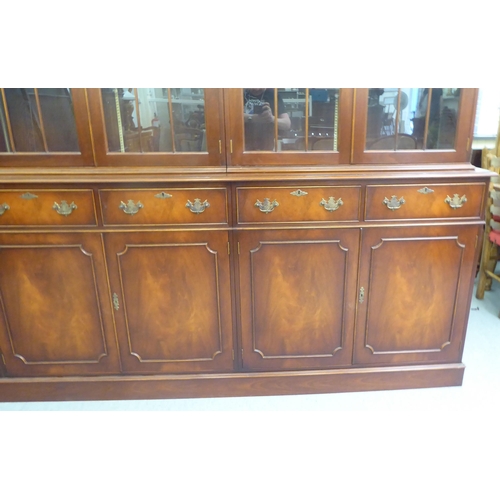 57 - A 20thC reproduction of a Georgian mahogany library bookcase, the upper section with three pairs of ... 